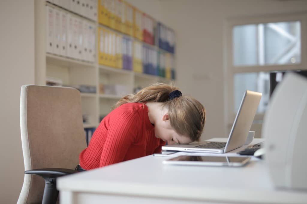 Time for an employee survey Woman at desk with head resting on keyboard of laptop
