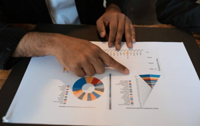 A man's hand pointing to a page with graphs